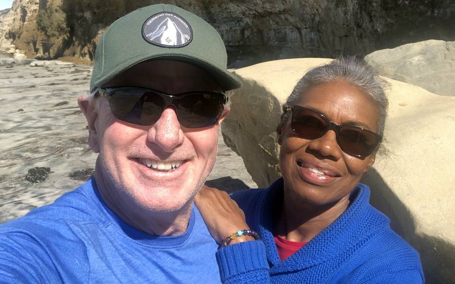 A mature interracial couple share a candid moment at the beach, representing their living kidney donation story at Scripps.