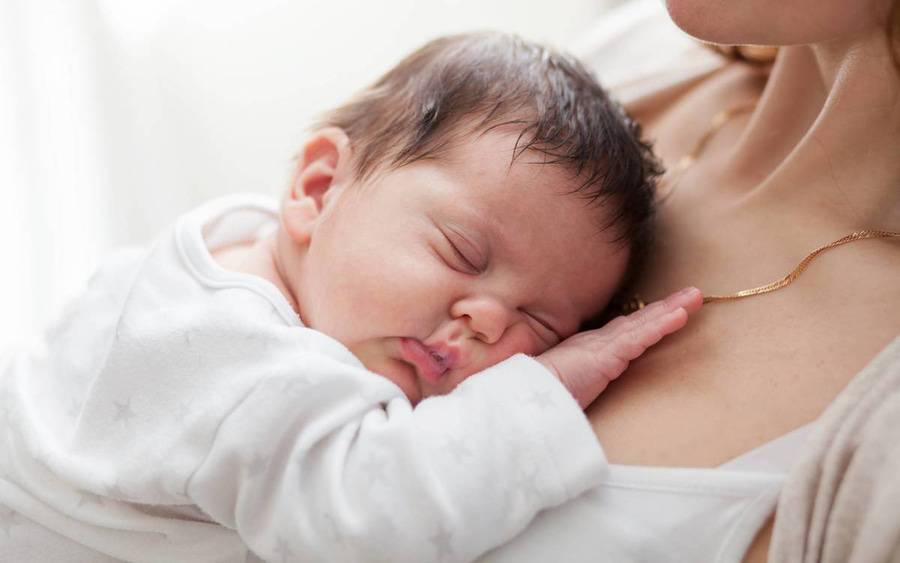 A mother holds her sleeping baby.