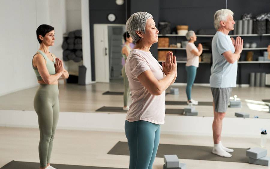 Men and women participate in a restorative yoga class learning simple stretches and poses that focuses on relaxation and rejuvenation.