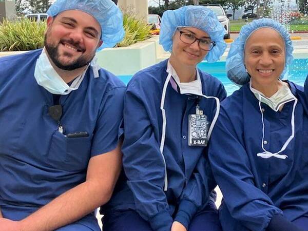 Four Scripps Health employees smile on a break outside a hospital facility in San Diego.