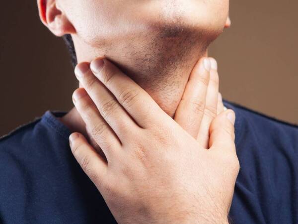 A man feels for lumps on his neck, looking for signs of head and neck cancer.