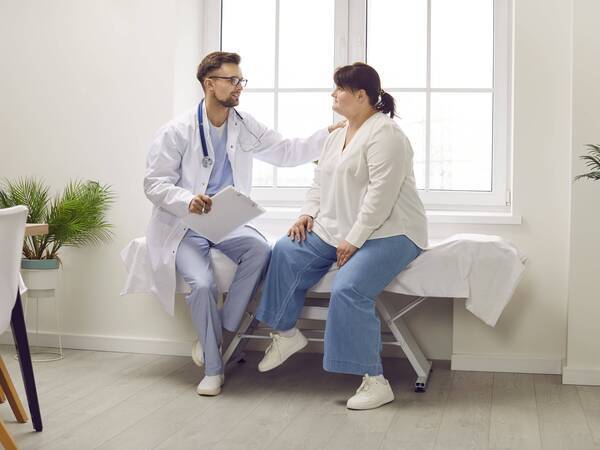 Doctor consulting obese patient on exam table
