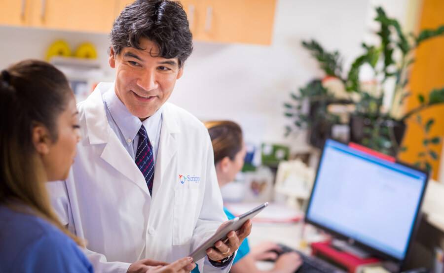 Gerald Lumking, MD, Family Medicine, Scripps Coastal Medical Center, physician discusses a treatment plan with another provider in a clinical office.