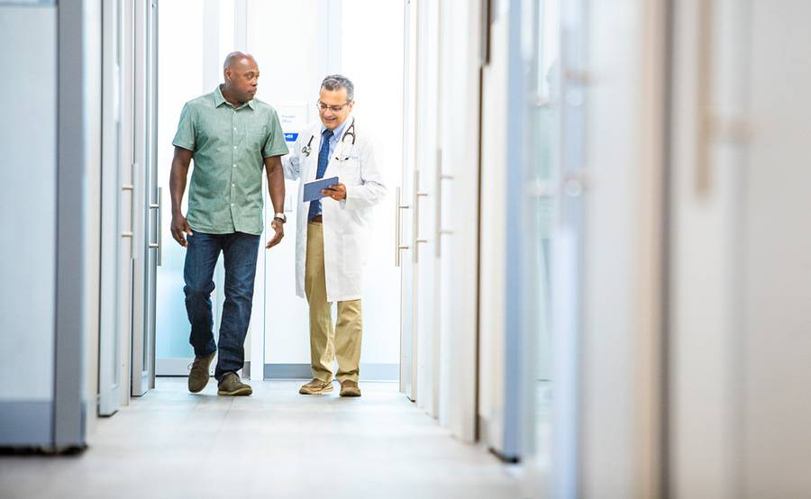Dr. Imran Ahmed, Family Medicine, Scripps Coastal Medical Center physician walking down a hallway with a patient discussing their recent appointment.