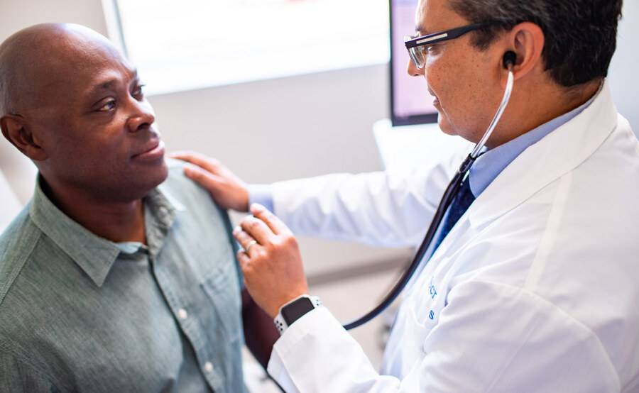 Dr. Imran Ahmed, Family Medicine physician for Scripps Coastal Medical Center speaking with a male patient.