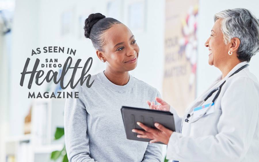 A young black woman smiles as she consults with her doctor. San Diego Health Magazine