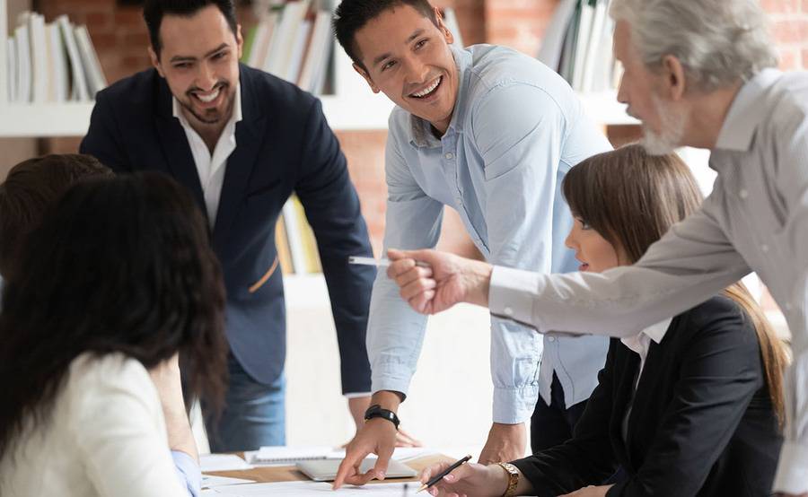 A group of employees having a work meeting and smiling.