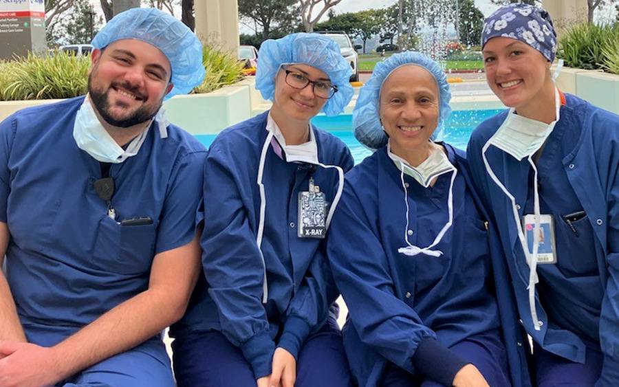 Four Scripps Health employees smile on a break outside a hospital facility in San Diego.