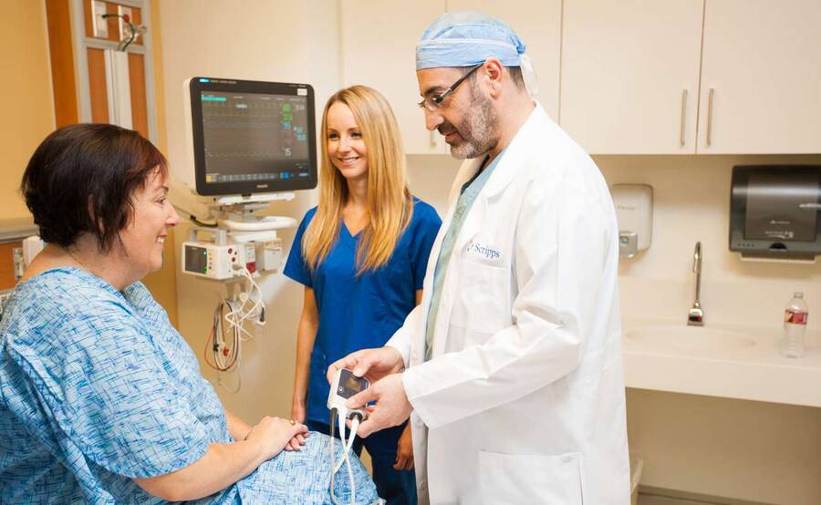 A male doctor and female nurse care for a mature female heart patient, representing LVAD and MCS at Scripps Health.