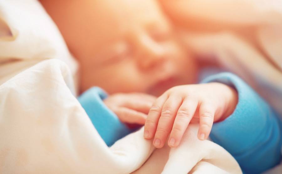 A newborn baby sleeps while wrapped in a soft blanket, representing the sensitive neonatal intensive care (NICU) Scripps provides in partnership with Rady Children’s Hospital.