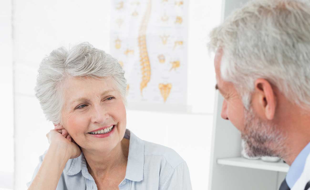 Mature woman discussing voice therapy with her doctor.