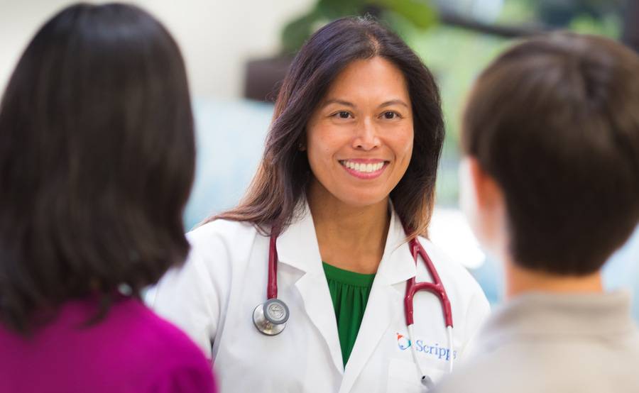 A female Scripps physician smiles at two people to show that Scripps is here for you.