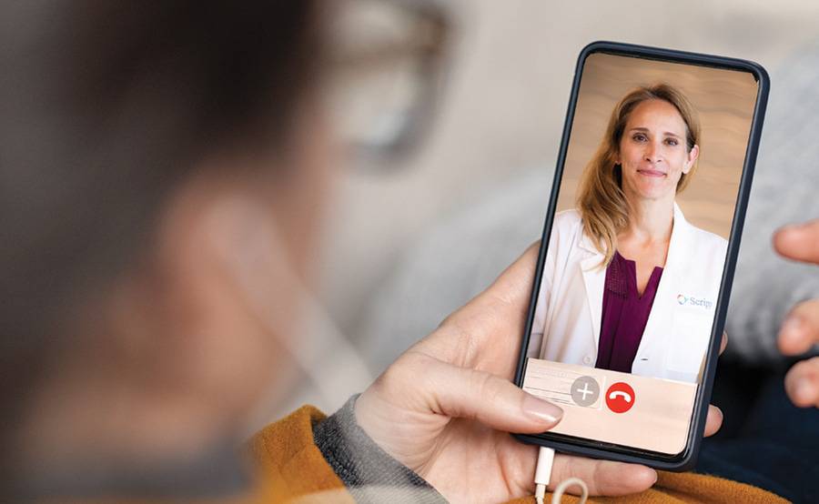 A female doctor smiles at a patient from a mobile device, representing telemedicine options at Scripps Health.