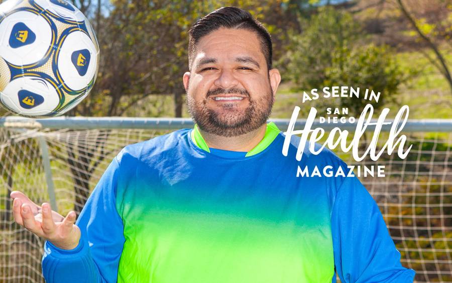Juan Ramos tosses a soccer ball in his hand in front of a soccer goal post. San Diego Health Magazine