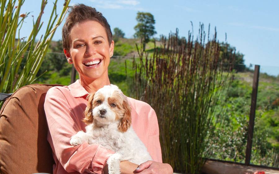 Kelly O'Connor wears a pink blouse and holds a small dog, representing her new purpose after breast cancer care at Scripps.