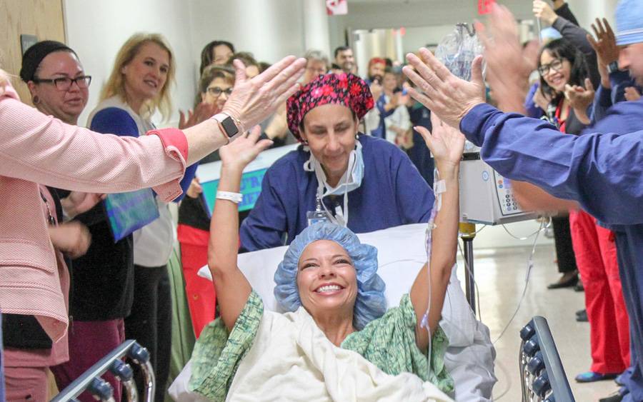 Hospital staff celebrate and high-five a patient as part of the Scripps Hero Walk program that celebrates living transplant donors.