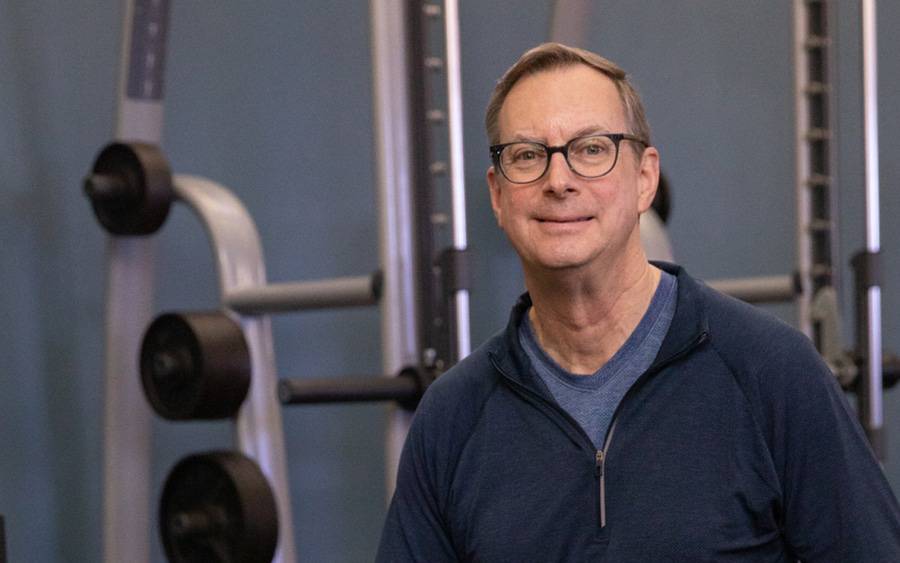 Keith Kendrick smiles near a weight rack after advanced technology at Scripps helped treat his hereditary heart issue.