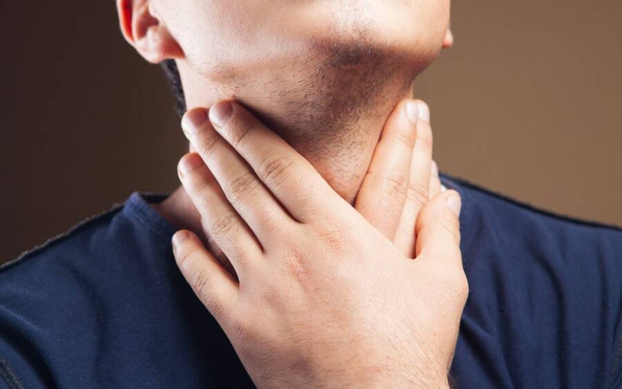 A man feels for lumps on his neck, looking for signs of head and neck cancer.