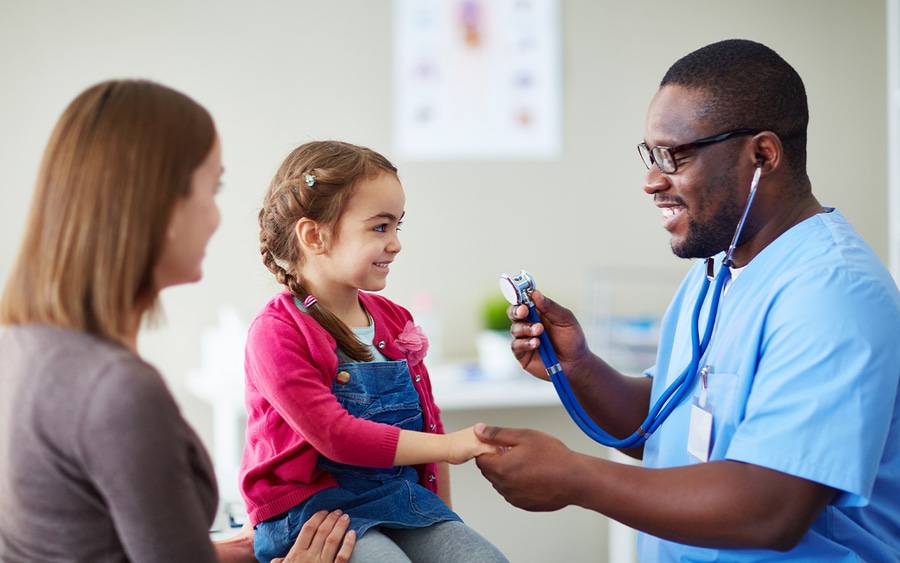 A pediatrician meets with mother and young girl for a wellness visit .