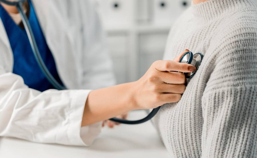 A doctor uses a stethoscope to check a patient's heart, representing Scripps Health's expertise in heart symptoms and causes.