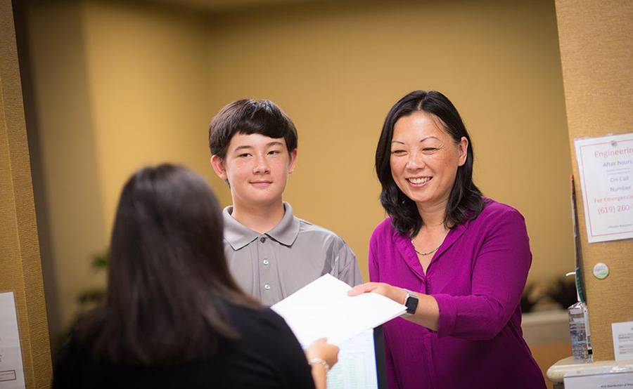 A mother and her son check-in at ScrippsHealth Express Hillcrest, illustrating the first step patients take when arriving at the walk-in clinic for same-day care.