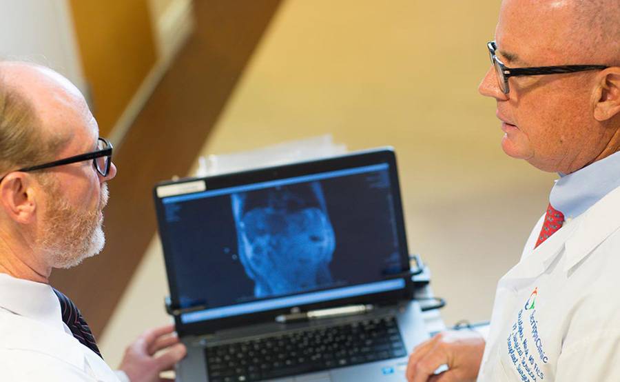 Two mature white doctors review a medical image on a laptop, representing blood and marrow transplant care at Scripps Health.