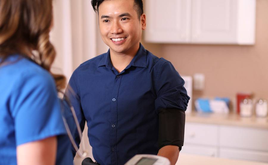 Male patient with a provider in clean brightly lit exam room at an express clinic.