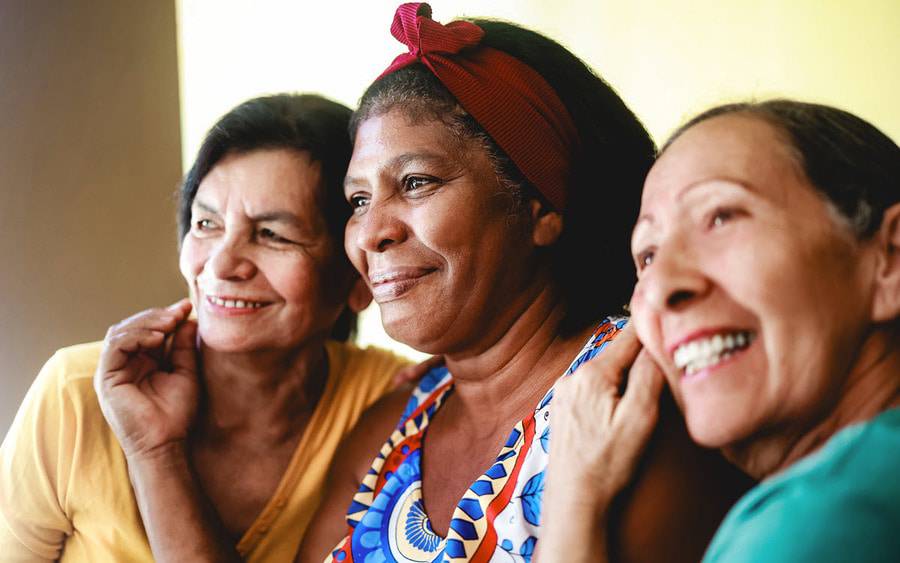 Three senior women smile as they participate in a group session for stroke and brain injury survivors.
