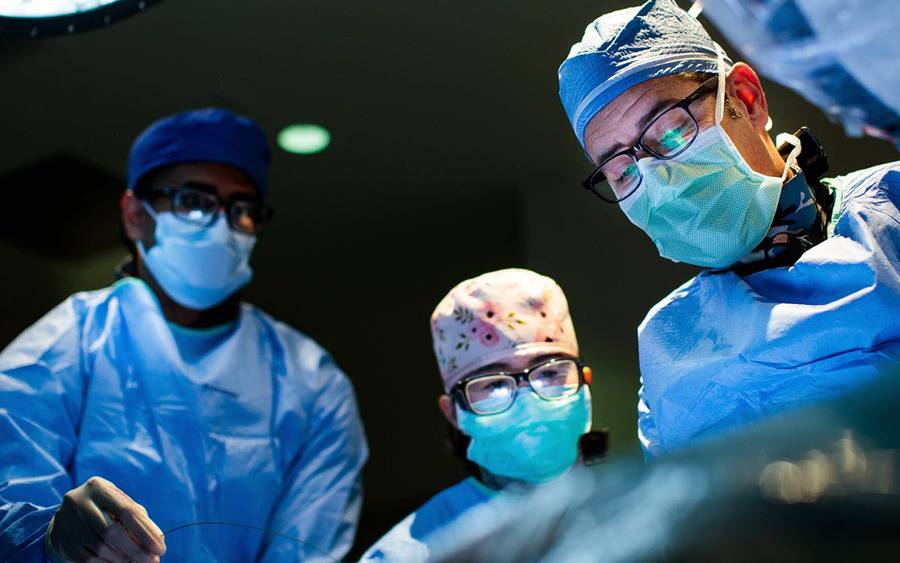 Surgeons and staff work on a patient in an operating room.