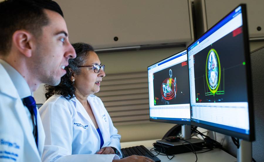 Two Scripps Cancer Center radiation oncologists review radiation therapy images on desktop monitors.