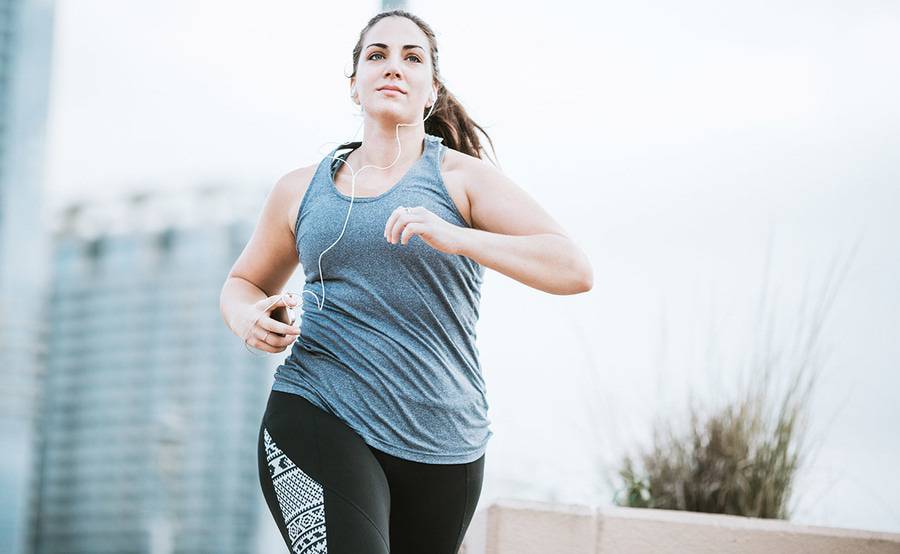 A woman running while wearing headphones, representing the active lifestyle people often enjoy following medically supervised weight management at Scripps.
