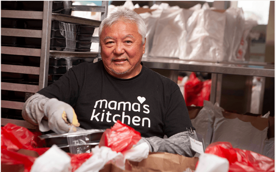 A mature multi-ethnic man smiles while serving prepared meals, representing a community benefit offering through Scripps.
