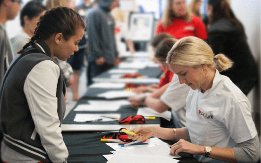 A woman reviews paperwork with a young athlete, representing the sudden cardiac arrest screening program through Scripps.